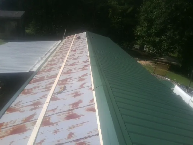 Old rusted panels beside newly installed green metal roofing — Wind Damage Roof Repair by Roofing Brothers in Rosalia
