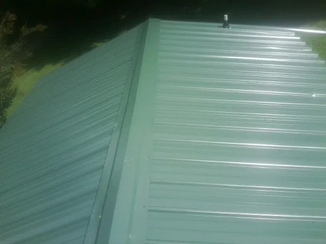 New green metal panels meeting at the ridge of a roof — Flat Roof Repair work by our crew in Rosalia