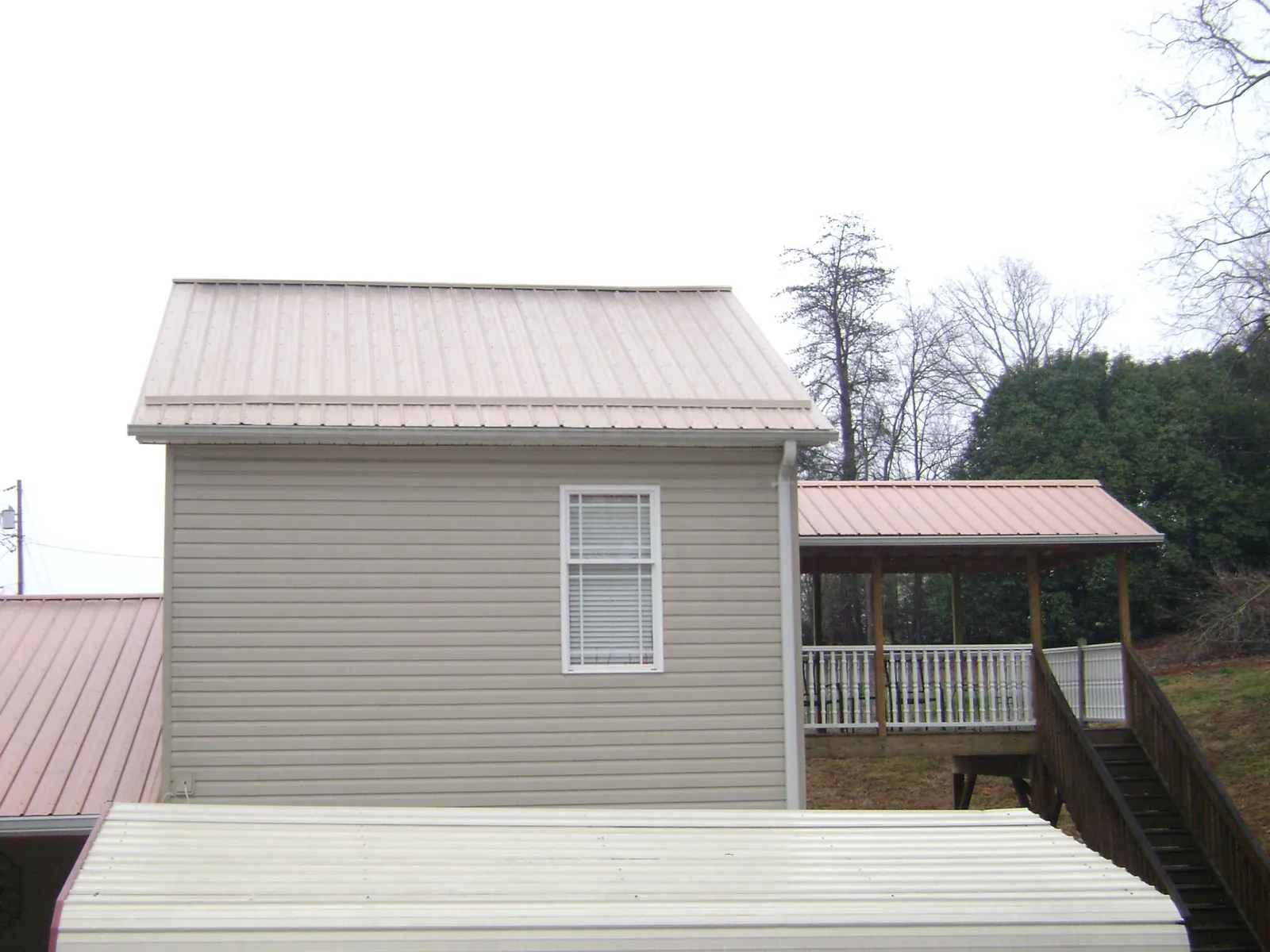 Tan metal roofs on a two story addition and attached porch, from a Roof Replacement job in Rosalia