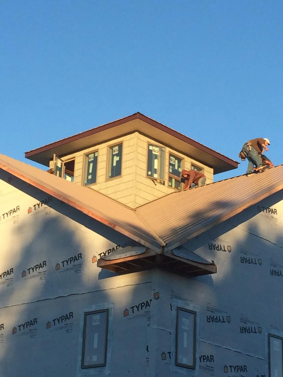 Roofers working around a rooftop cupola on a new metal roof at sunset — Roof Waterproofing in Rosalia by Roofing Brothers